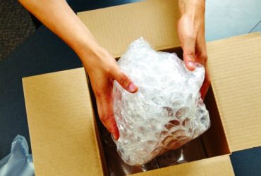 hands putting a bubble wrapped item in a box