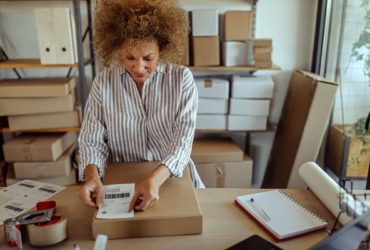 A woman affixes a shipping label to a box (iStock)