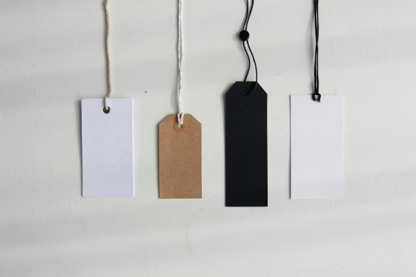 A row of clothing tags next to each other varying in size, shape, and colour.