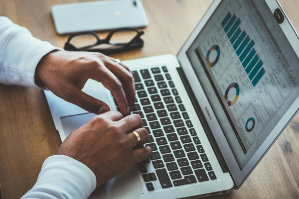 Person typing on laptop that displays charts and graphs