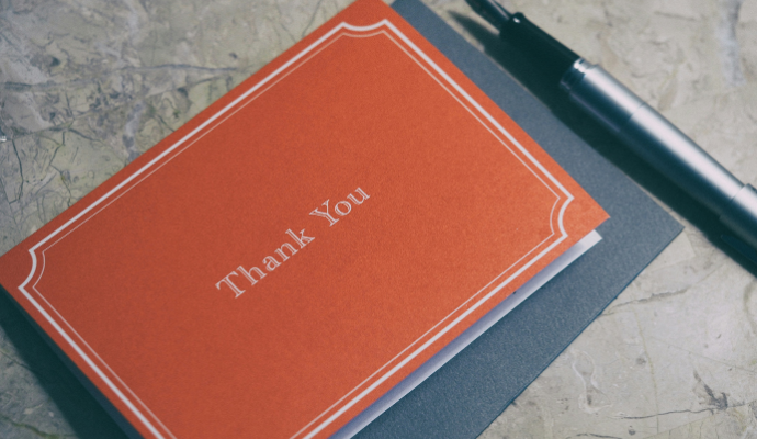 Une petite carte rouge pliée sur laquelle on peut lire « Merci » au recto