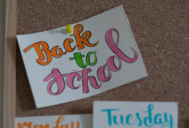 Card pinned to cork board that says "back to school" in colourful cursive writing