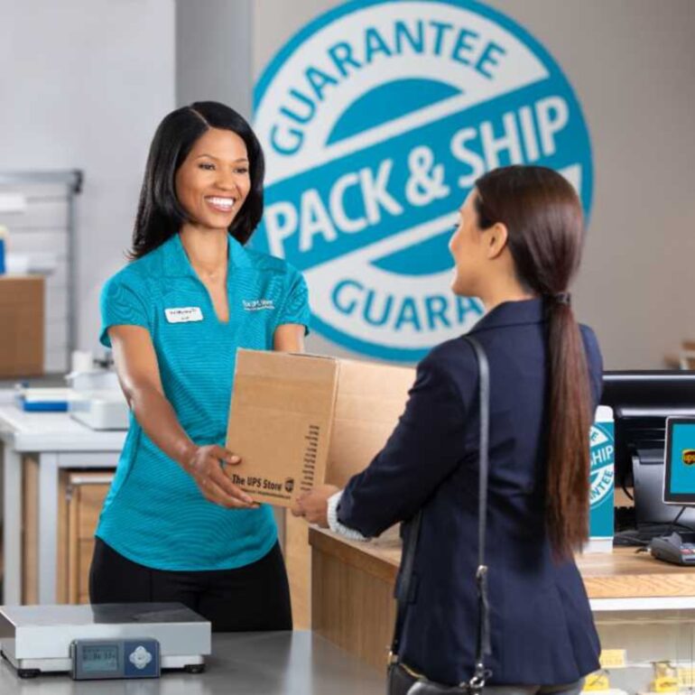 Customer handing over cardboard box to shipping professional to ship at The UPS Store
