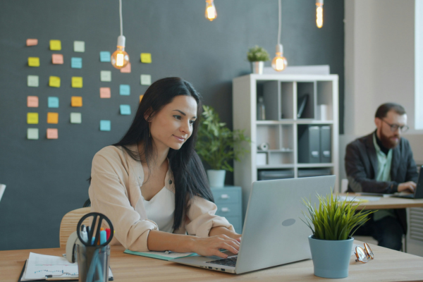Two employees in an offie setting sitting at their desk