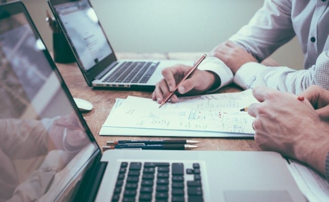 Deux personnes parlant et discutant avec un ordinateur portable sur la table du bureau.