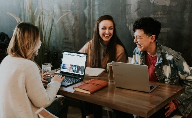 Heureux jeunes assis dans le café à l'aide d'un ordinateur portable