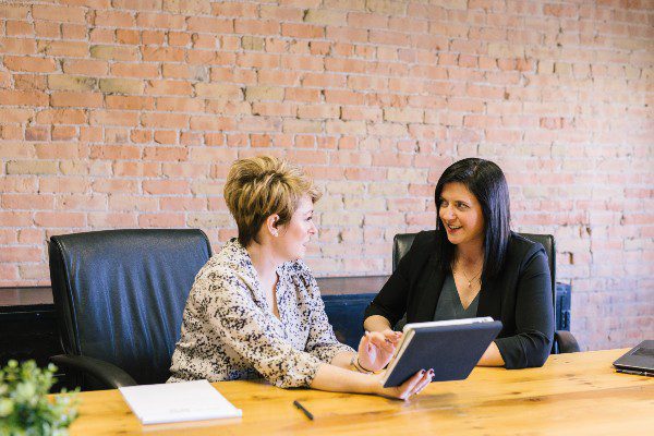 Two women sitting in front of a laptop