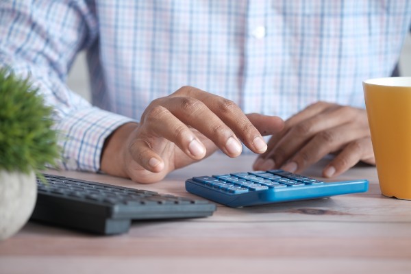 a man's hand using a blue calculator
