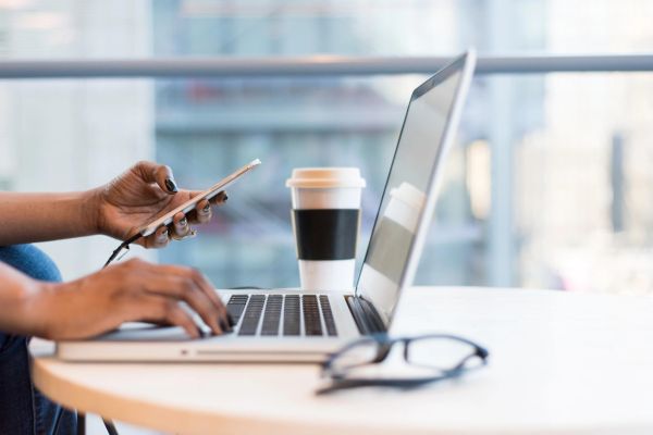 Person on their computer and mobile phone at desk