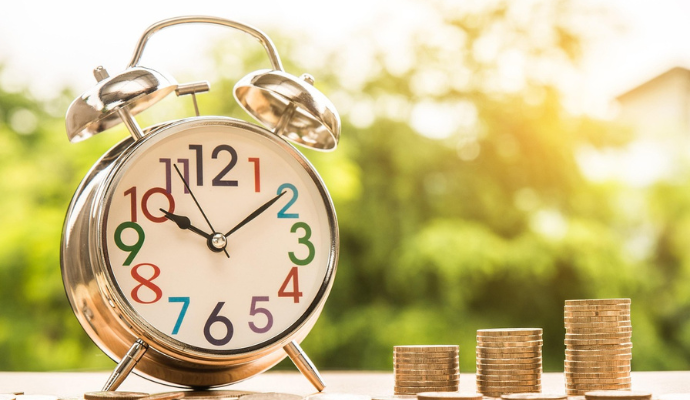 Standing clock on desk next to small piles of coins