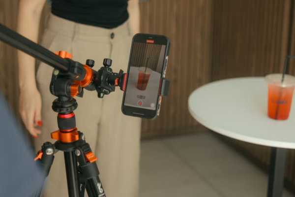 Tripod holding a mobile phone that is recording a drink.