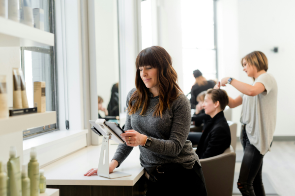 A woman looking at tablet inside of a hair salon