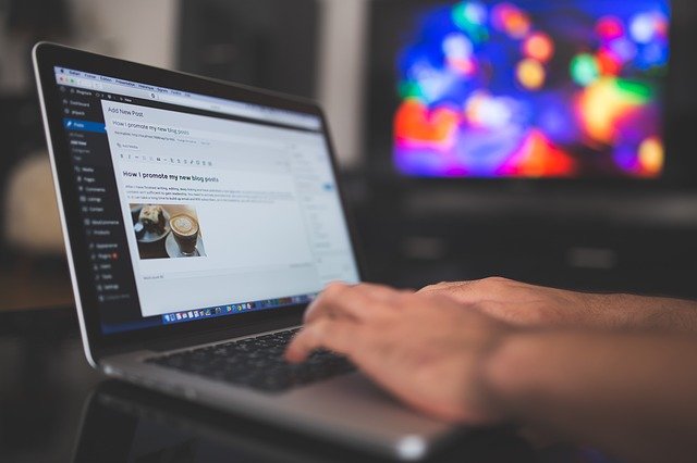 Hands typing on a laptop that's showing a Wordpress blog page