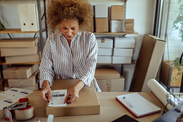 A woman affixes a shipping label to a box